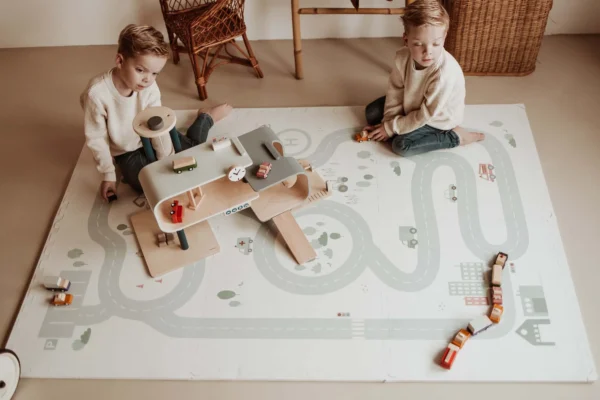 Duas crianças a brincar com carrinhos e brinquedos abertos no tapete de EVA da Play&Go.